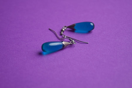 silver earrings with a blue stone on a purple backgroundの写真素材