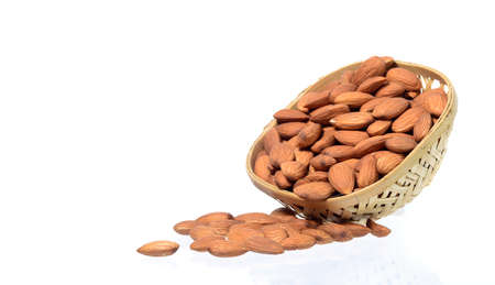 Almonds in a wooden basket with heap isolated on a white backgroundの写真素材