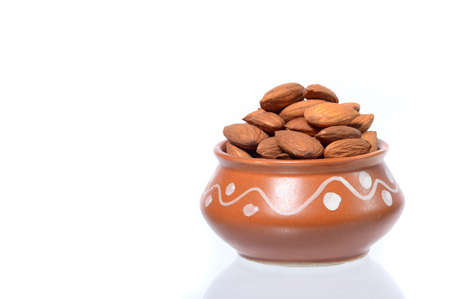 Almonds in a clay pot isolated on a white backgroundの写真素材