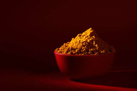 Dry Turmeric powder and roots or barks in red bowl on red backgroundの写真素材