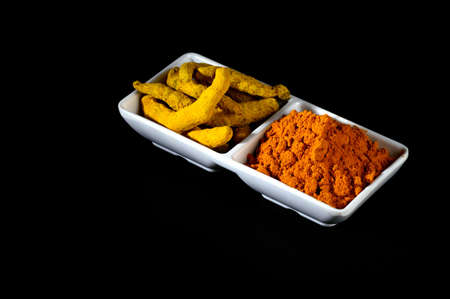 Dry Turmeric powder and roots or barks in white plateの写真素材