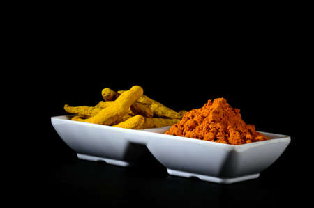 Dry Turmeric powder and roots or barks in white plateの写真素材