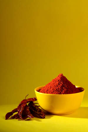 chili powder in yellow bowl on yellow background. Red chilly pepperの写真素材