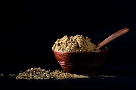 Coriander Powder in wooden bowl with seeds on black backgroundの写真素材