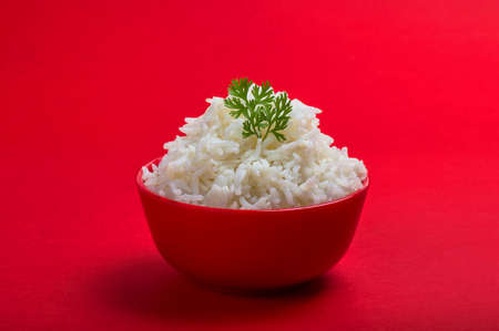 Cooked plain white basmati rice in a red bowl on red backgroundの写真素材