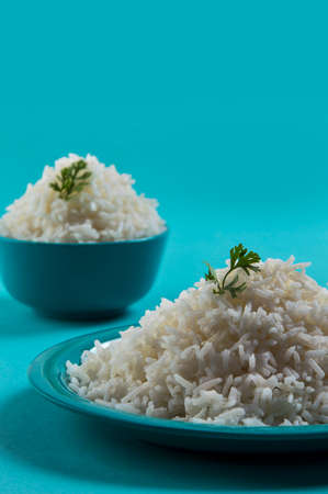 Cooked plain white basmati rice in a blue plate and bowl on blue backgroundの写真素材