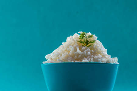 Cooked plain white basmati rice with corriander in a blue bowl on blue backgroundの写真素材