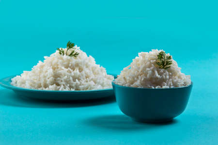 Cooked plain white basmati rice in a blue plate and bowl on blue backgroundの写真素材