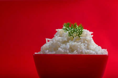 Cooked plain white basmati rice in a red bowl on red backgroundの写真素材