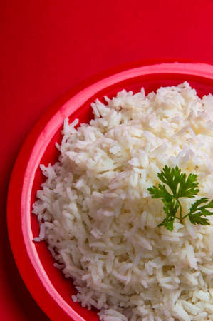 Cooked plain white basmati rice in a red plate on red backgroundの写真素材