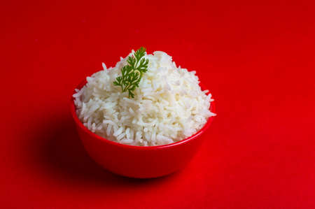 Cooked plain white basmati rice in a red bowl on red backgroundの写真素材