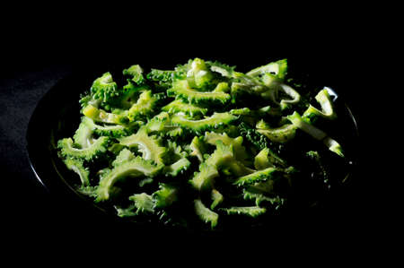 Bitter melon or bitter gourd in black plate on black background.の写真素材