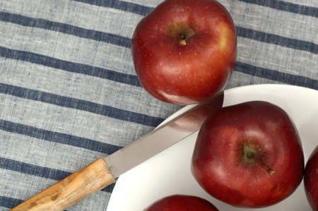 Delicious Apples in plate with knife on striped tableclothの写真素材