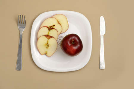 Delicious apple and slice in white plate with knife and forkの写真素材
