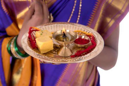 Indian woman performing worship, portrait of a beautiful young lady with pooja thali isolated on white backgroundの写真素材