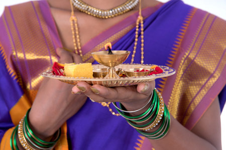 Indian woman performing worship, portrait of a beautiful young lady with pooja thali isolated on white backgroundの写真素材