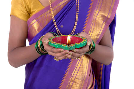 Portrait of a woman holding diya, Diwali or deepavali photo with female hands holding oil lamp during festival of light on white backgroundの写真素材