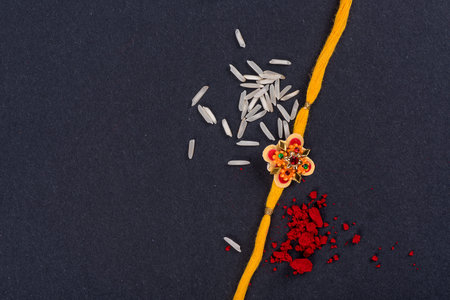 Raksha Bandhan : Rakhi with rice grains and kumkum on black background, Traditional Indian wrist band which is a symbol of love between Brothers and Sisters.の写真素材