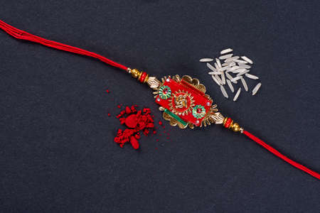 Raksha Bandhan : Rakhi with rice grains and kumkum on black background, Traditional Indian wrist band which is a symbol of love between Brothers and Sisters.の写真素材