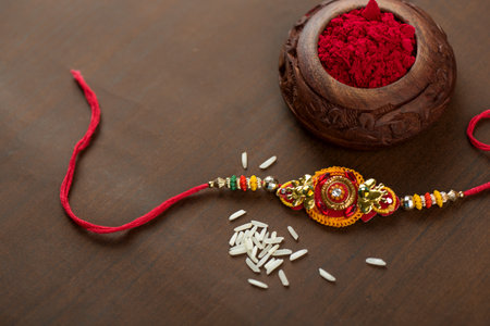 Indian festival: Raksha Bandhan background with an elegant Rakhi, Rice Grains and Kumkum. A traditional Indian wrist band which is a symbol of love between Brothers and Sisters.の写真素材