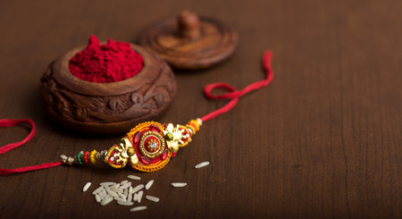 Indian festival: Raksha Bandhan background with an elegant Rakhi, Rice Grains and Kumkum. A...
