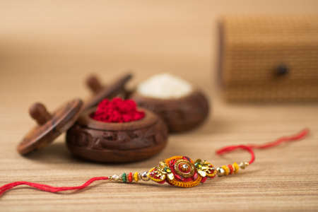 Indian festival: Raksha Bandhan background with an elegant Rakhi, Rice Grains and Kumkum. A traditional Indian wrist band which is a symbol of love between Brothers and Sisters.の写真素材
