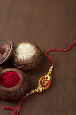 Indian festival: Raksha Bandhan background with an elegant Rakhi, Rice Grains and Kumkum. A traditional Indian wrist band which is a symbol of love between Brothers and Sisters.の写真素材