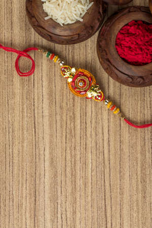 Indian festival: Raksha Bandhan background with an elegant Rakhi, Rice Grains and Kumkum. A traditional Indian wrist band which is a symbol of love between Brothers and Sisters.の写真素材