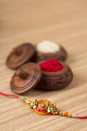 Indian festival: Raksha Bandhan background with an elegant Rakhi, Rice Grains and Kumkum. A traditional Indian wrist band which is a symbol of love between Brothers and Sisters.の写真素材