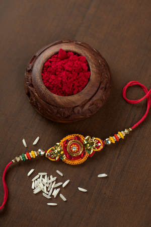 Indian festival: Raksha Bandhan background with an elegant Rakhi, Rice Grains and Kumkum. A traditional Indian wrist band which is a symbol of love between Brothers and Sisters.の写真素材