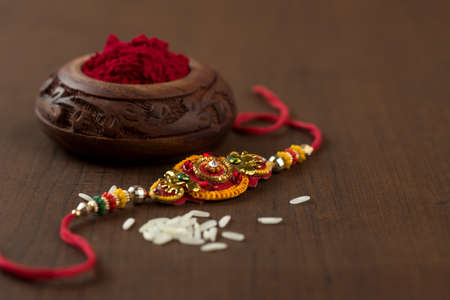 Indian festival: Raksha Bandhan background with an elegant Rakhi, Rice Grains and Kumkum. A traditional Indian wrist band which is a symbol of love between Brothers and Sisters.の写真素材