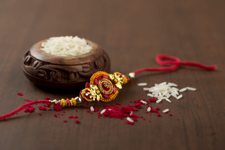 Indian festival: Raksha Bandhan background with an elegant Rakhi, Rice Grains and Kumkum. A traditional Indian wrist band which is a symbol of love between Brothers and Sisters.の写真素材