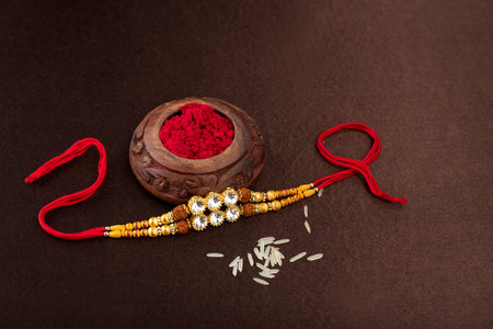 Raksha Bandhan background with an elegant Rakhi, Rice Grains and Kumkum. A traditional Indian wrist...