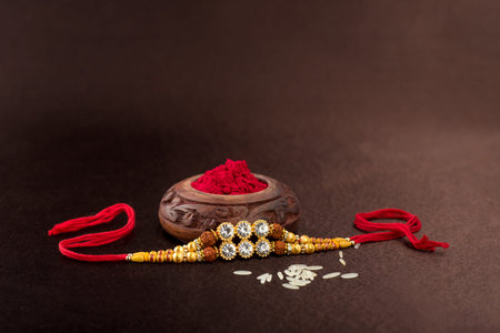 Raksha Bandhan background with an elegant Rakhi, Rice Grains and Kumkum. A traditional Indian wrist...