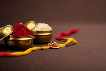 Raksha Bandhan background with an elegant Rakhi, Rice Grains and Kumkum. A traditional Indian wrist band which is a symbol of love between Brothers and Sisters.の写真素材