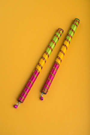 Dandiya sticks on a yellow background. Raas Garba or Dandiya Raas is the traditional folk dance form the state of Gujarat & Rajasthan in India.の写真素材