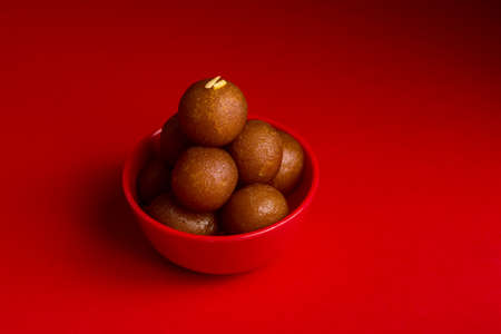 Gulab Jamun in red bowl on red background. Indian Dessert or Sweet Dish.の写真素材