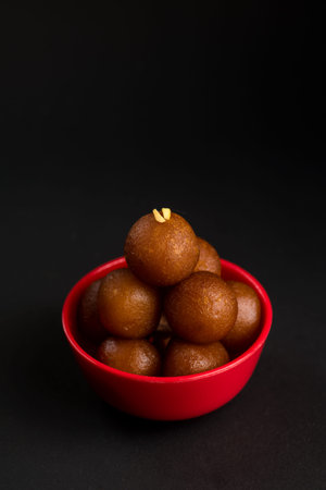 Gulab Jamun in bowl on black background. Indian Dessert or Sweet Dish.