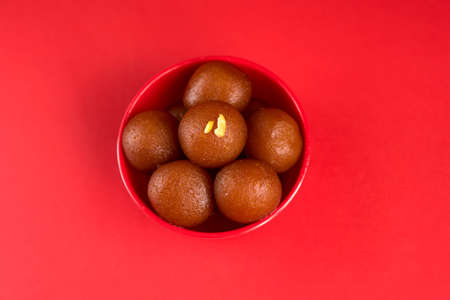 Gulab Jamun in red bowl on red background. Indian Dessert or Sweet Dish.の写真素材
