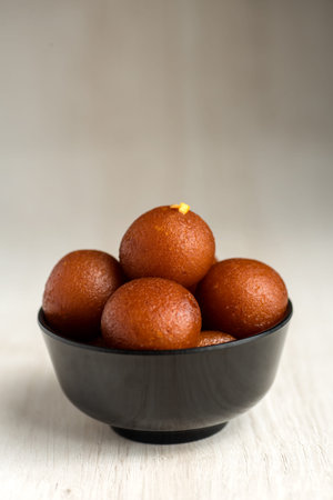 Indian Dessert or Sweet Dish : Gulab Jamun in bowl on wooden background.