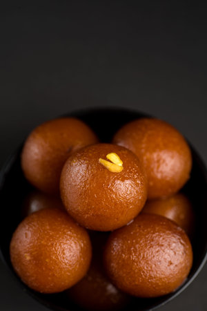 Gulab Jamun in bowl on black background. Indian Dessert or Sweet Dish.