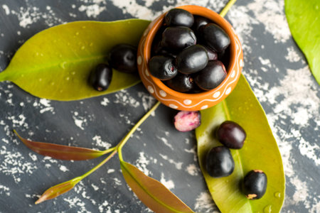 Jambolan plum or jambul or Jamun fruit, Java plum (Syzygium cumini) with leaf on stone textured...