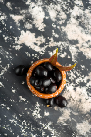 Jambolan plum or jambul or Jamun fruit, Java plum (Syzygium cumini) with leaf on stone textured...