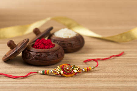Indian festival: Raksha Bandhan background with an elegant Rakhi, Rice Grains and Kumkum. A traditional Indian wrist band which is a symbol of love between Brothers and Sisters.の写真素材