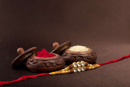 Raksha Bandhan background with an elegant Rakhi, Rice Grains and Kumkum. A traditional Indian wrist band which is a symbol of love between Brothers and Sisters.の写真素材