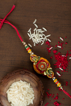Indian festival: Raksha Bandhan background with an elegant Rakhi, Rice Grains and Kumkum. A...