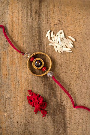 Indian festival: Raksha Bandhan background with an elegant Rakhi, Rice Grains and Kumkum. A...