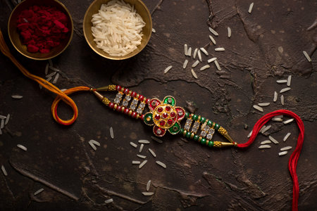 Raksha Bandhan background with an elegant Rakhi, Rice Grains and Kumkum. A traditional Indian wrist...