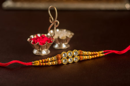 Indian festival: Raksha Bandhan background with an elegant Rakhi, Rice Grains and Kumkum. A...