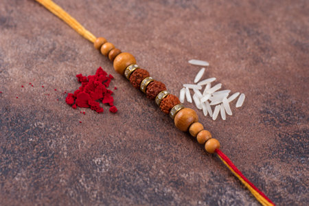 Raksha Bandhan : Rakhi with rice grains and kumkum on stone background, Traditional Indian wrist...